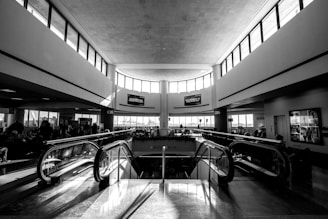 A modern escalator ascending inside a bustling airport terminal in Qatar with travelers and luggage.