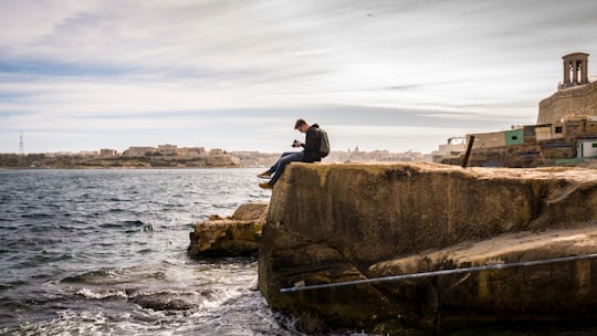 man sitting on brown rock near sea at daytime in Valletta Malta