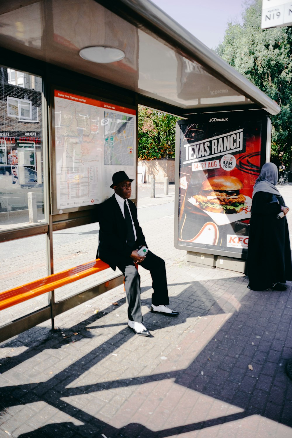 man sitting on orange bench beside woman standing