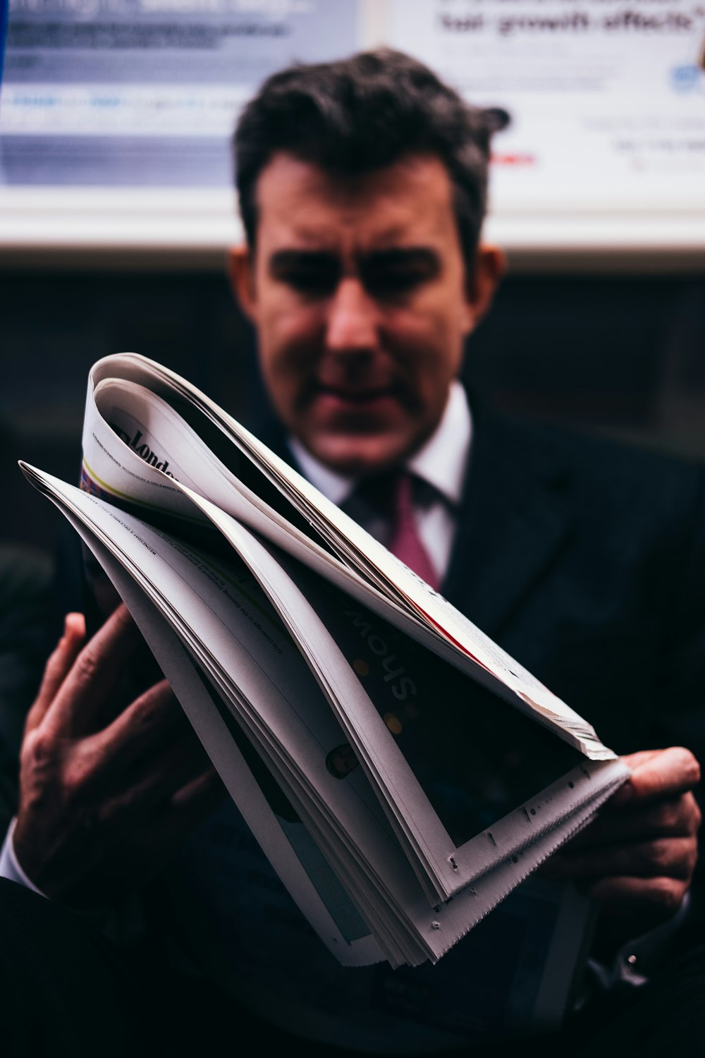 selective focus photo of man in suit holding newspaper
