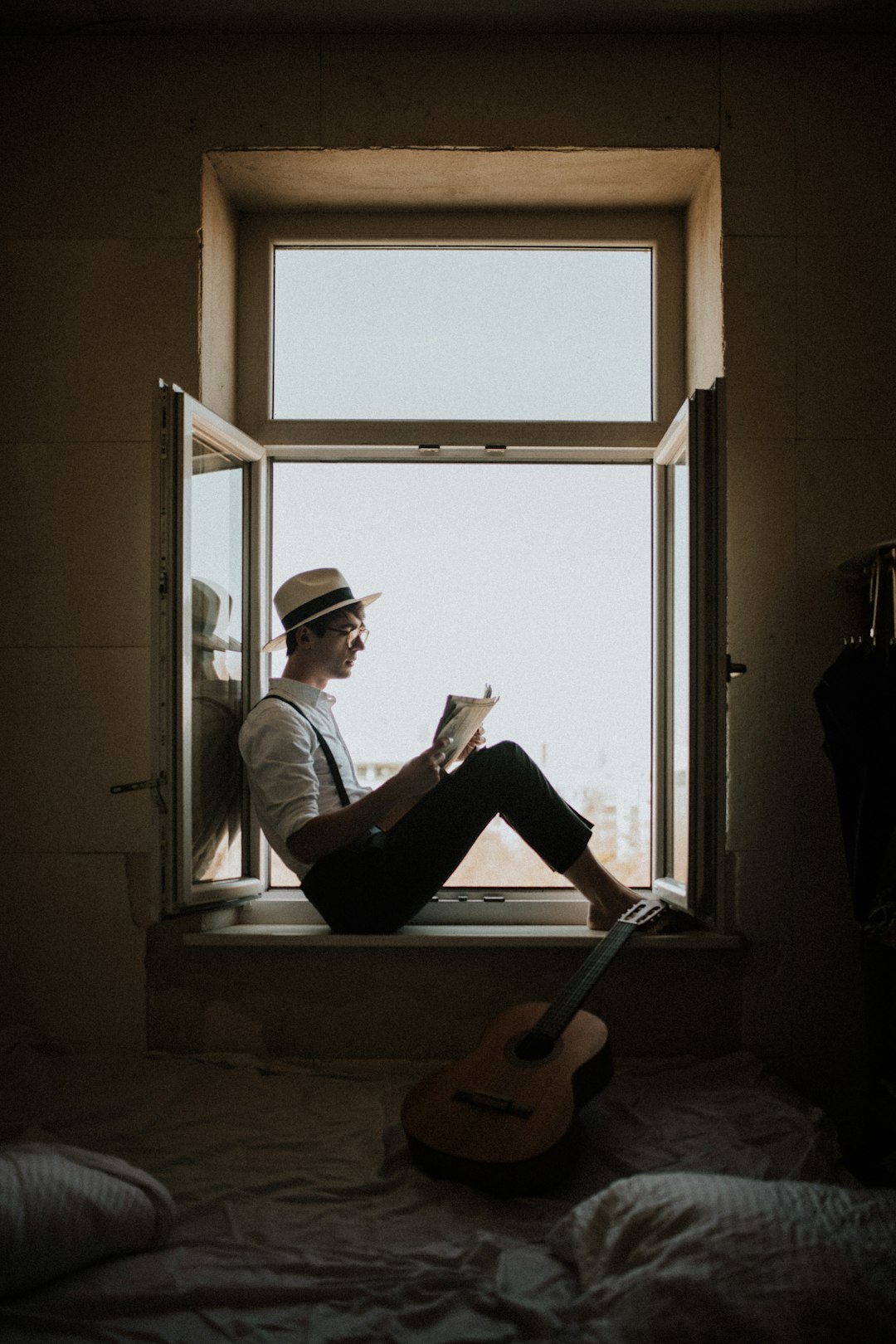 man sitting on window while reading