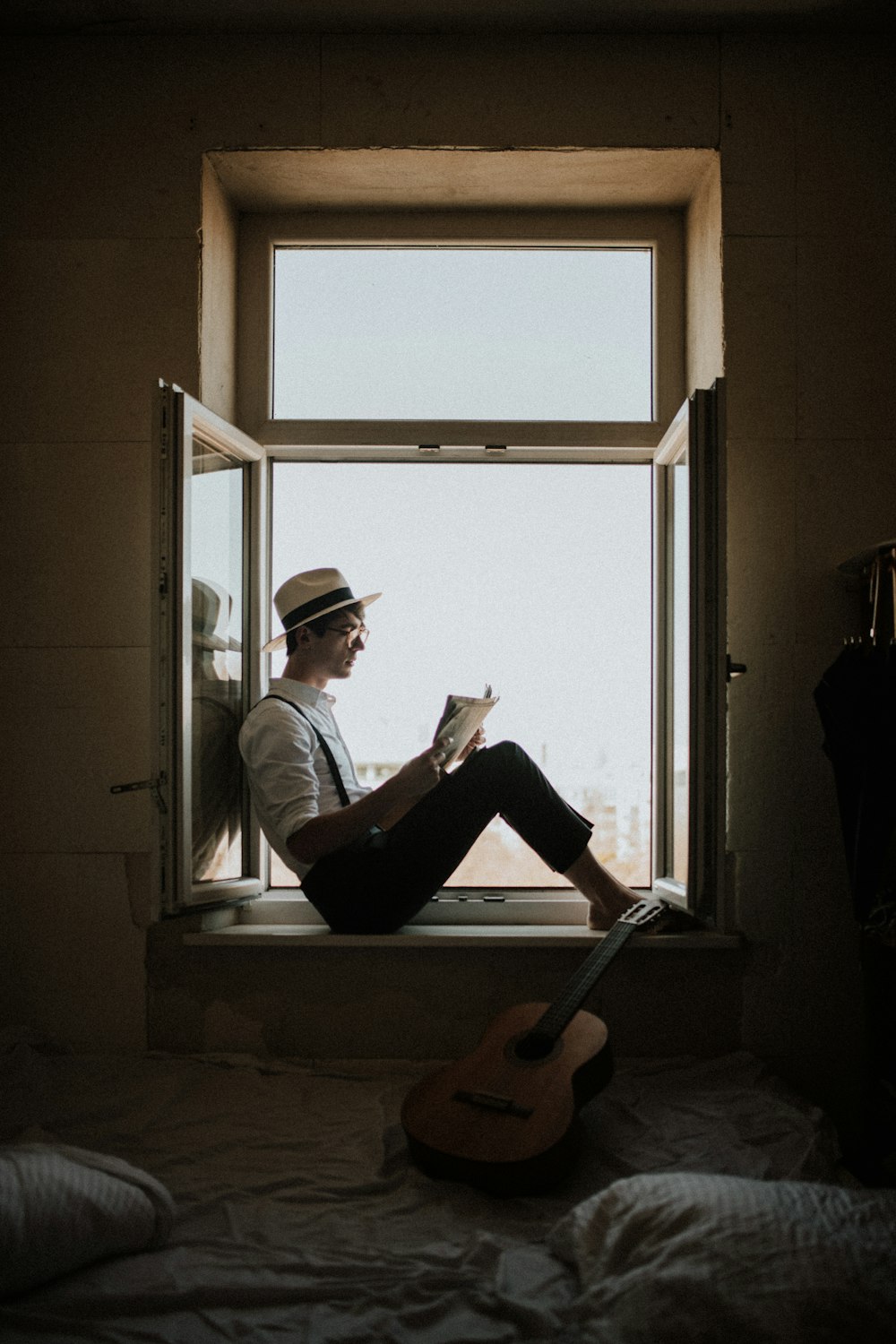 hombre sentado en la ventana mientras lee