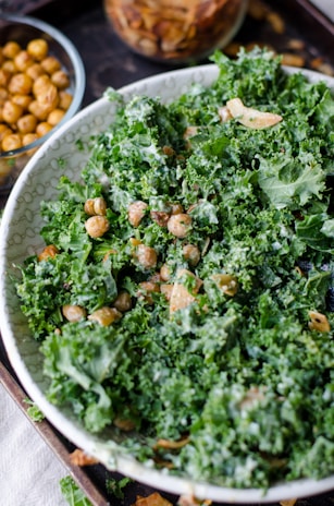 A bowl filled with crisp kale salad topped with roasted chickpeas and a tangy dressing.
