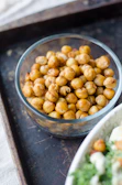 Artful arrangement of roasted chickpeas and vegetables on a soft green ceramic dish.