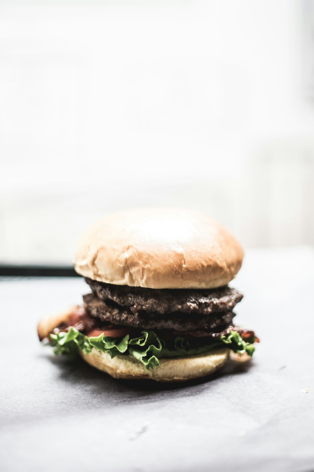 hamburger con lattuga e pomodoro su superficie grigia