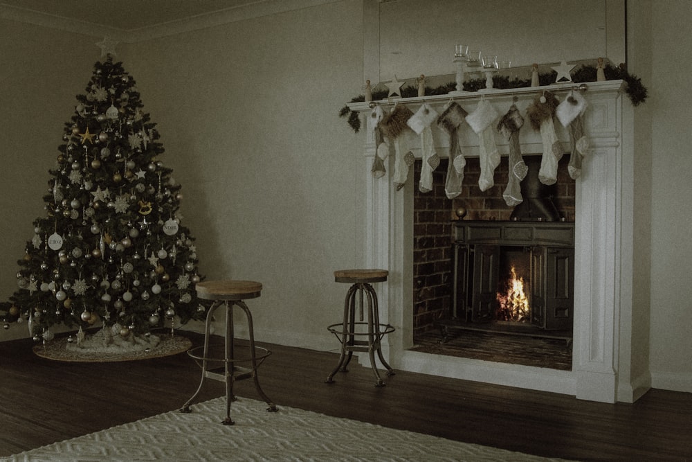 Árbol de Navidad cerca de dos taburetes en la chimenea