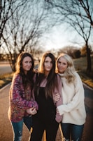 shallow focus photography of three women standing along trees