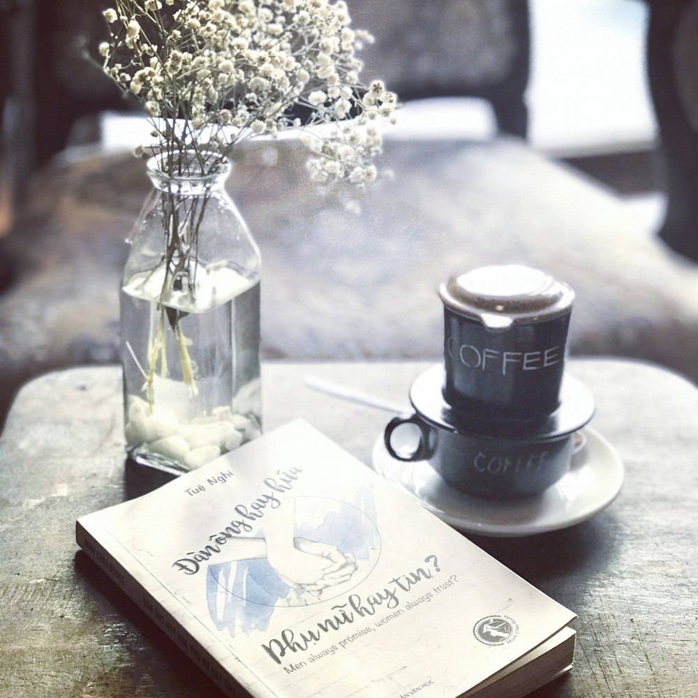 labeled book near teacup and saucer and vase