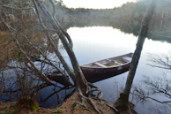 A calm river winding through autumn-colored trees with a wooden canoe resting at the shore.
