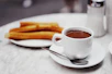 cup of chocolate drink with plate of churros