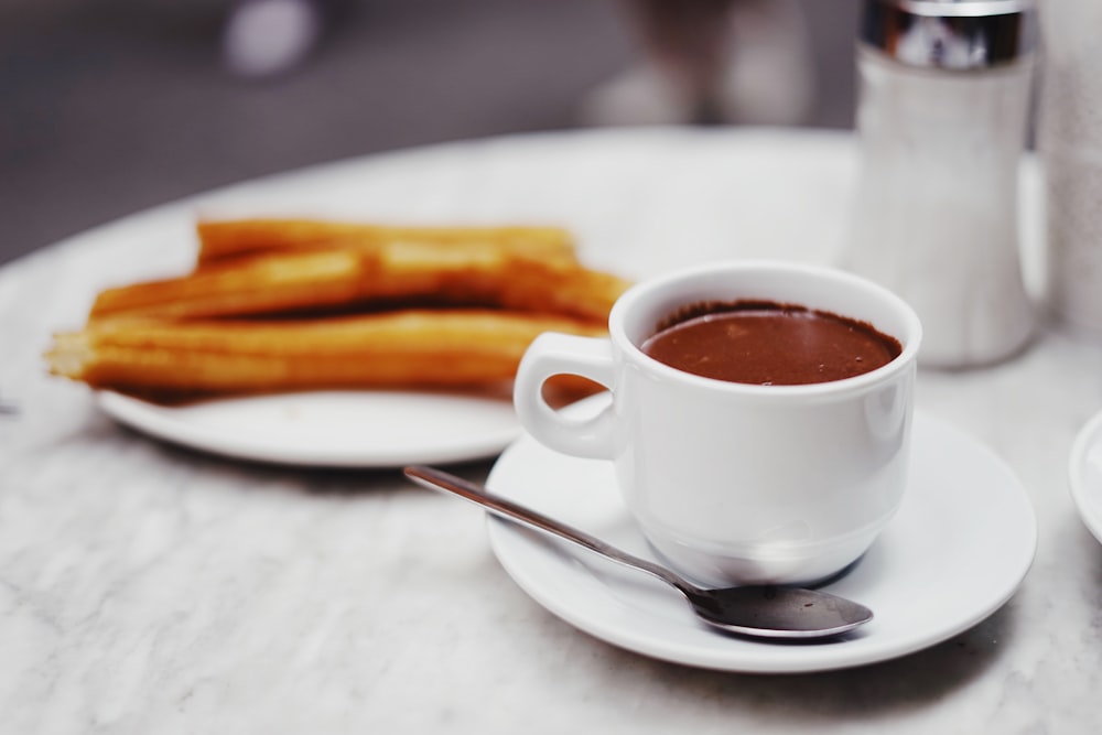 taza de bebida de chocolate con plato de churros