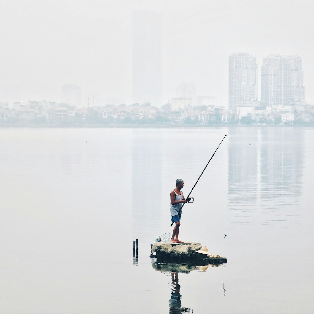 hombre de pie en la roca sosteniendo la caña de pescar