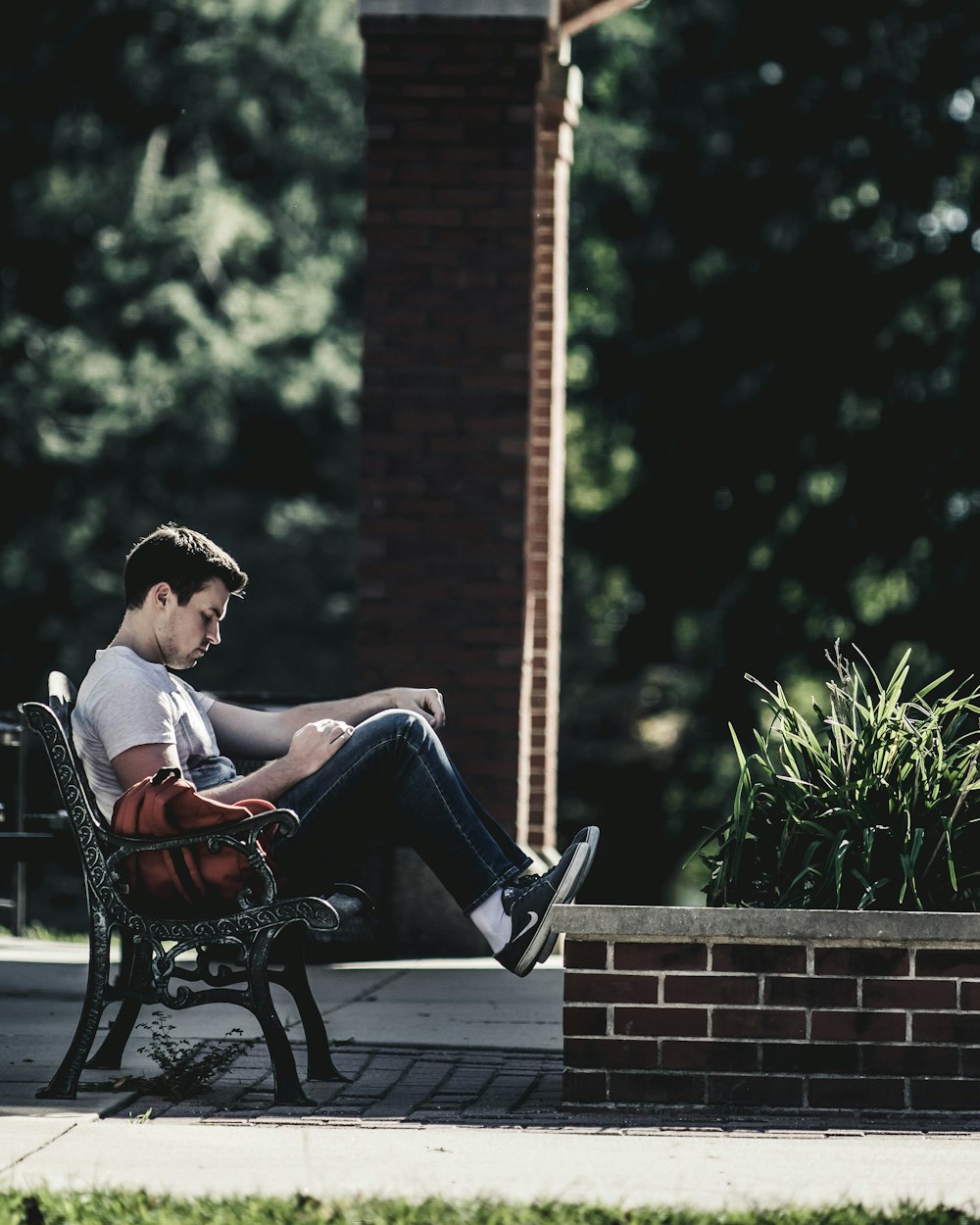 man wearing gray crew-neck t-shirt sitting on black metal bench