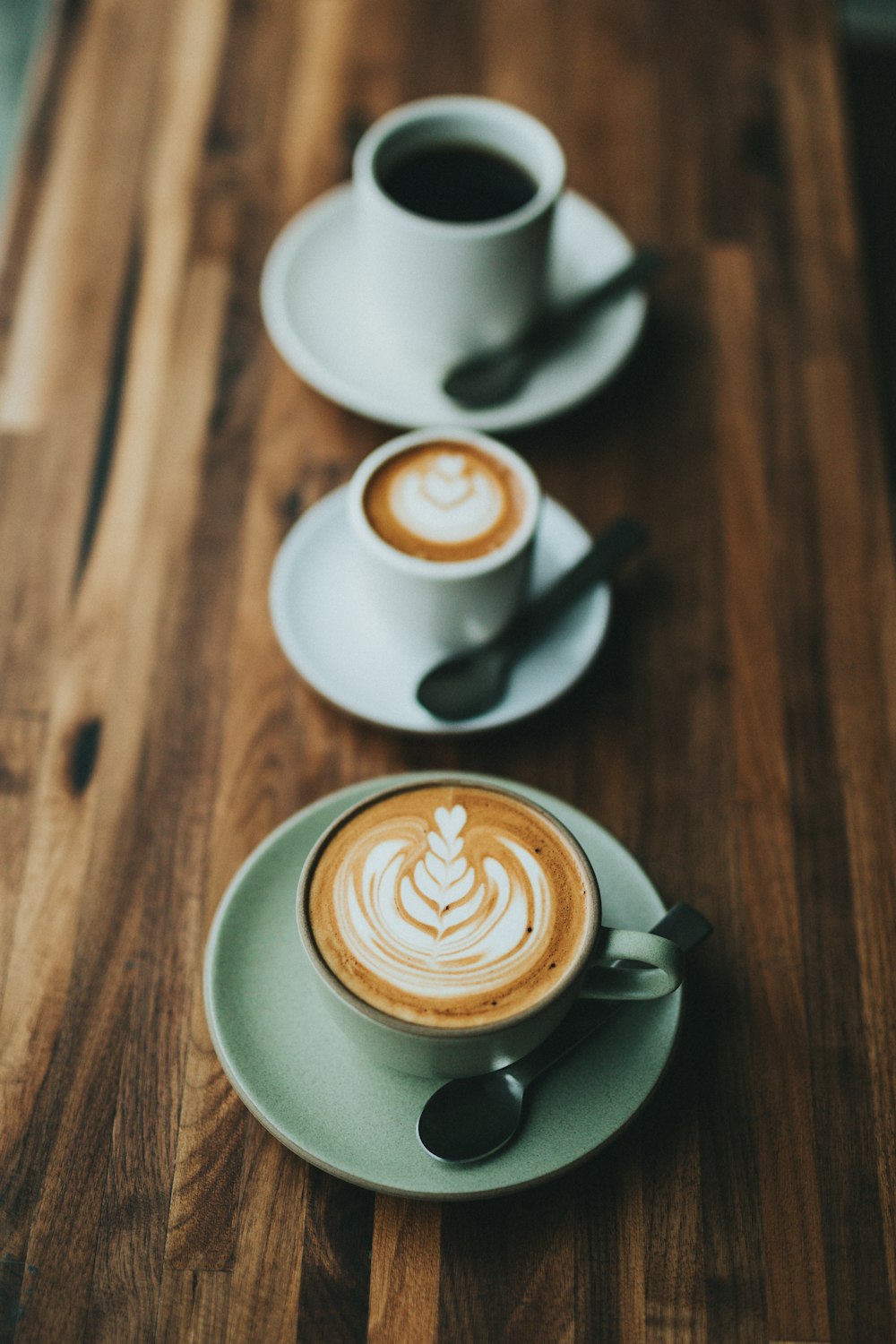 white coffee cup on saucer with teaspoon filled with coffee and frothed milk