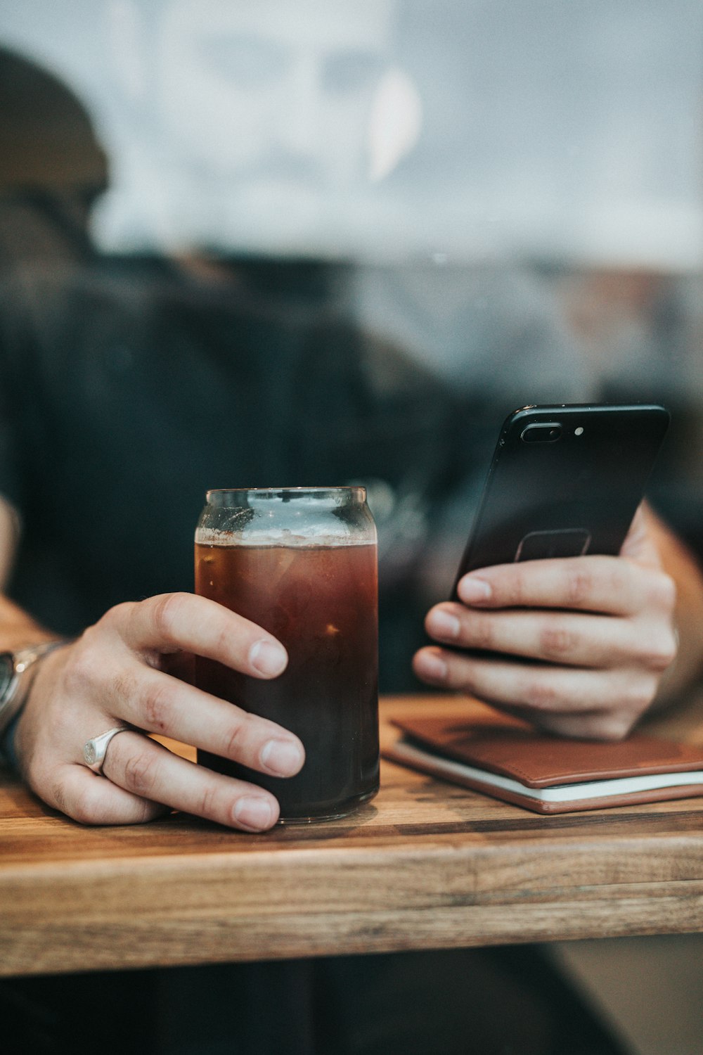 Person mit Trinkglas und Smartphonwe