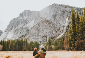 person standing on grass field while carrying child