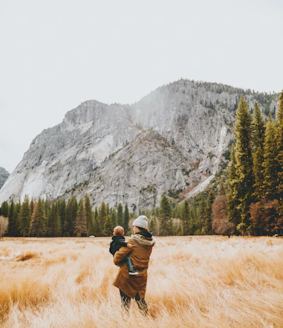person standing on grass field while carrying child