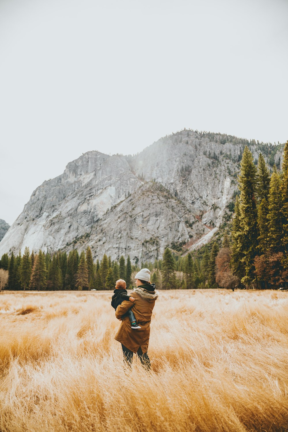 person standing on grass field while carrying child