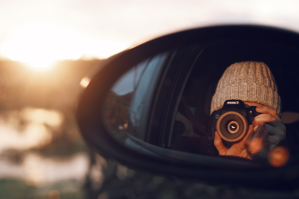 vehicle's side mirror reflecting person taking photo using Canon DSLR camera
