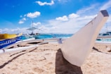 Sandy shore with colorful boats lined up at Porto de Galinhas under a bright blue sky.