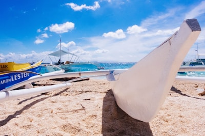 Sandy shore with colorful boats lined up at Porto de Galinhas under a bright blue sky.
