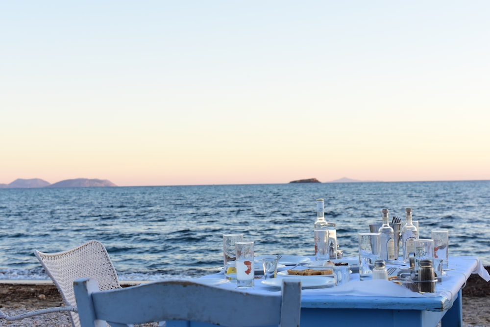 blue table with white chair near body of water