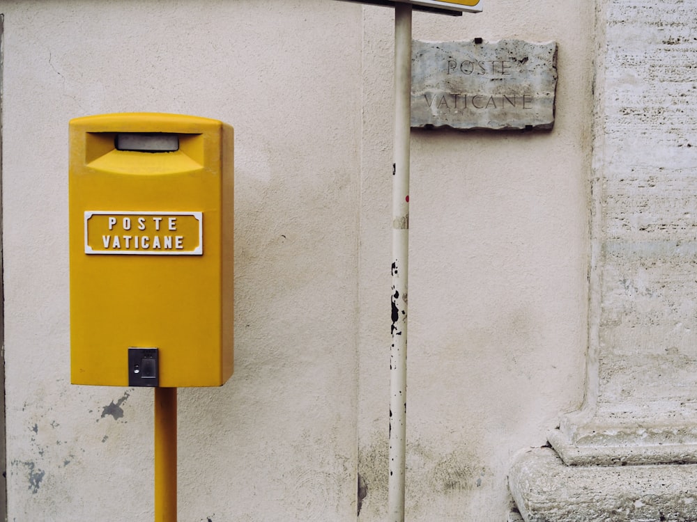 Medidor amarillo Poste Vaticane junto a la pared blanca