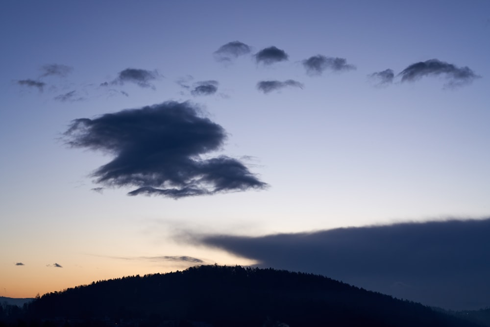 silhouette of hill under cloudy sky