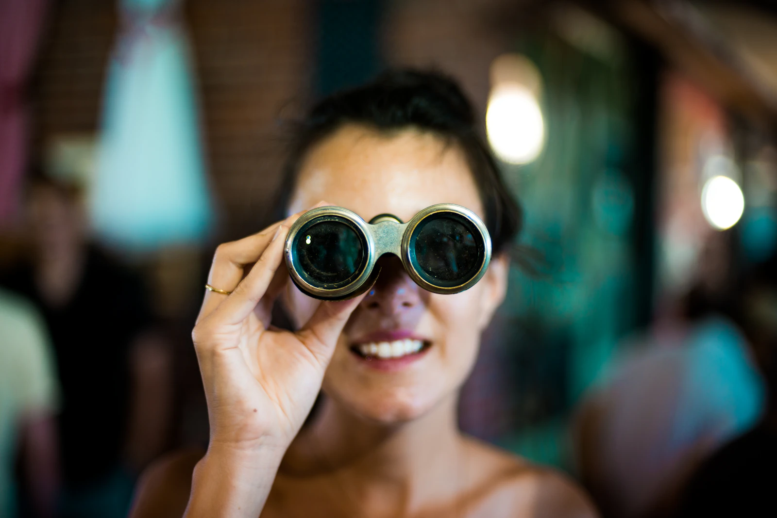 Woman using gray binoculars to look into the distance, representing what Search Console's Generative AI report can show a site owner: visibility into impressions, without the click that follows