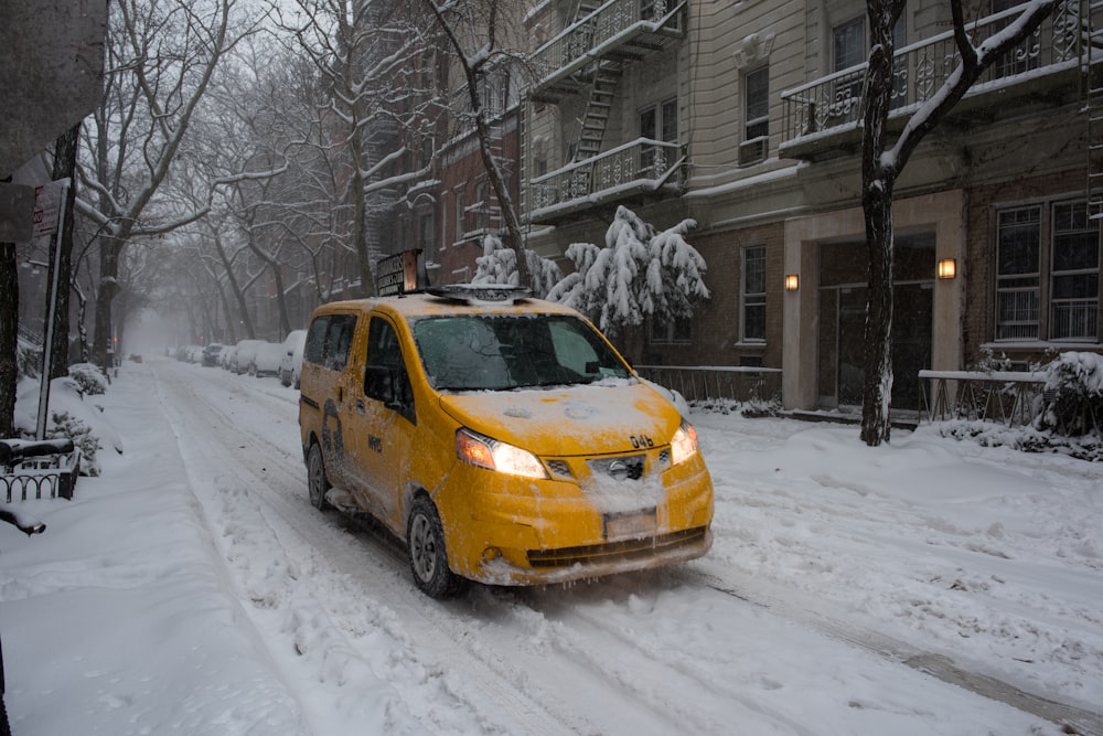 yellow sedan on snow covered road during daytime