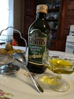 Artisan smoked extra virgin olive oil bottle next to fresh olives on a wooden table.