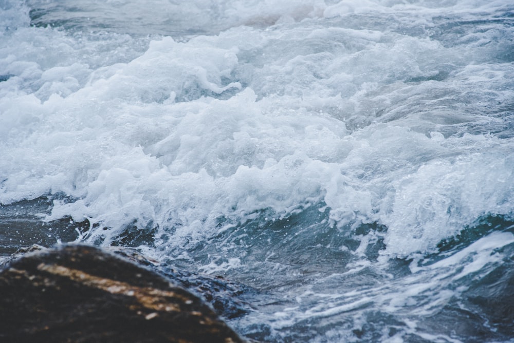 body of water splashing on brown rock closeup photo