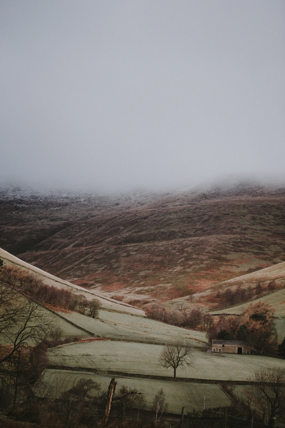 Serene mountain range with foggy peaks and village in foreground amidst autumnal winter landscape