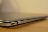Side angle showing slim design and ports of Dell notebook on a wooden desk.