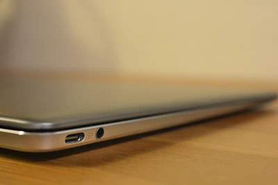 Side angle showing slim design and ports of Dell notebook on a wooden desk.