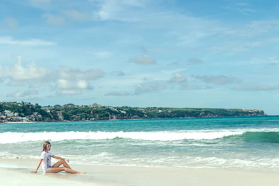 A serene beach scene with a person wearing a windbreaker and sunglasses from Brisamont.