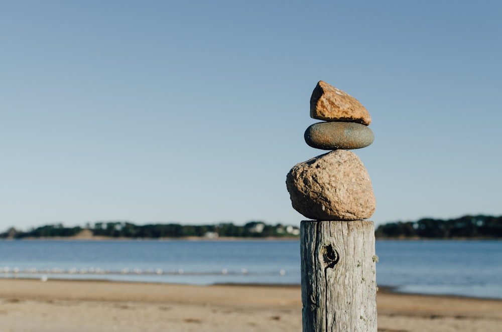 Equilibrio de rocas en un poste de madera cerca del cuerpo de agua