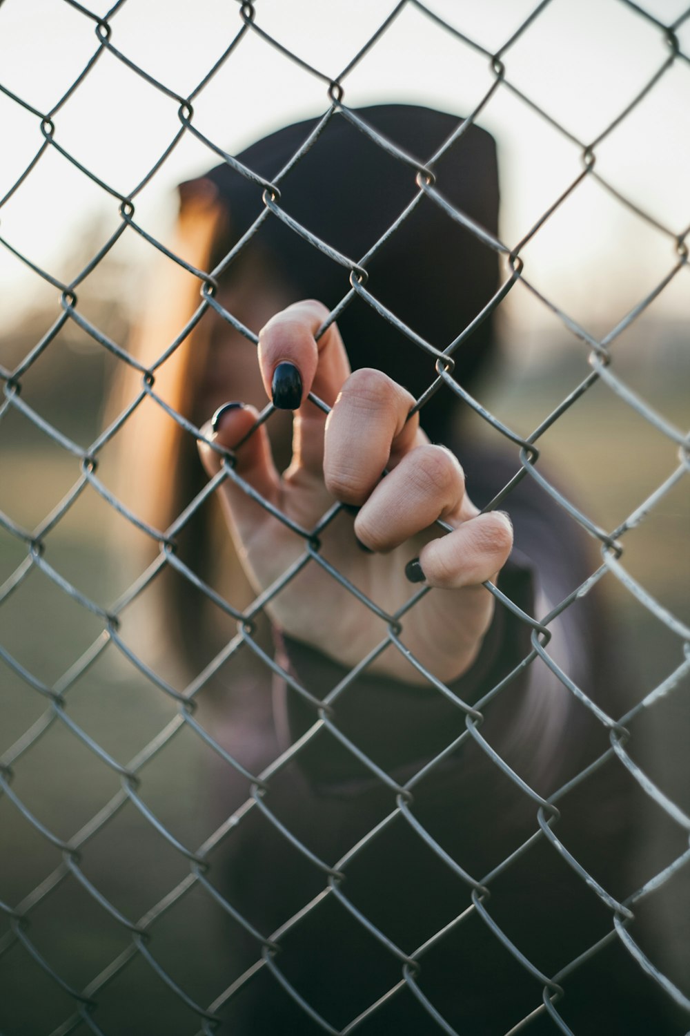 person holding on gray metal fence