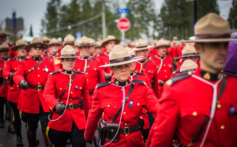 um grupo de homens com uniformes vermelhos marchando por uma rua