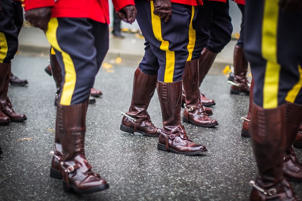 selective-focus photography of people wearing brown patent leather knee-high boots walking across street