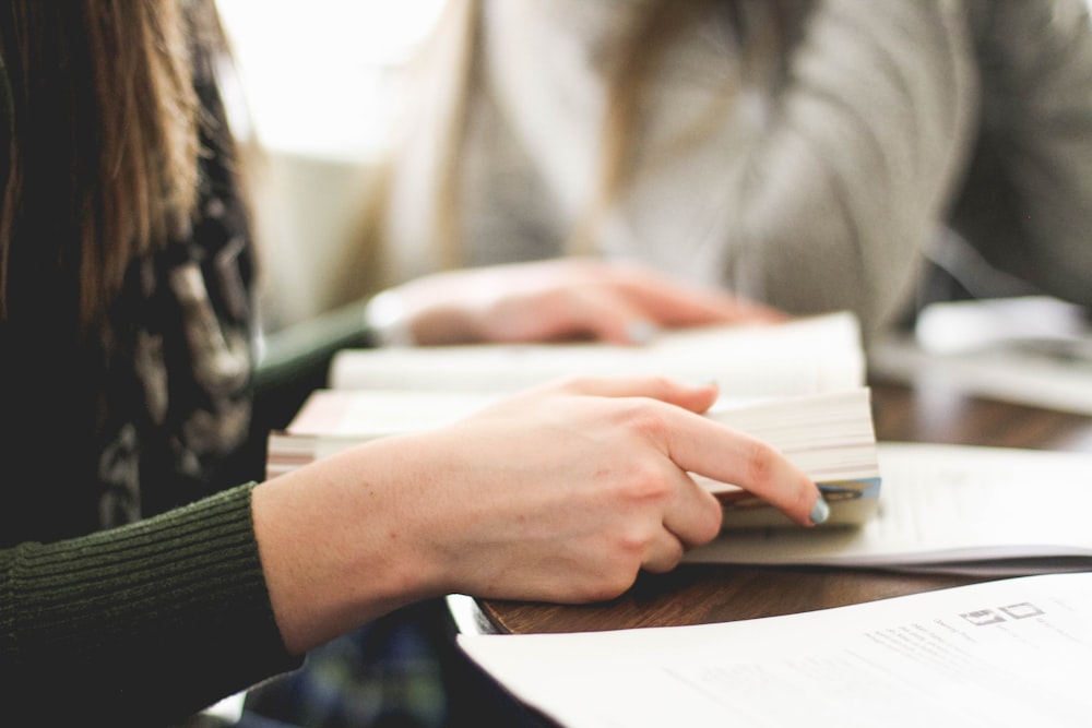 donna seduta sulla sedia davanti al libro di lettura bianco del tavolo