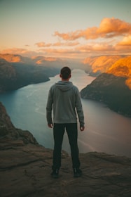Baha standing on a cliff overlooking the fjords of Norway at sunset.