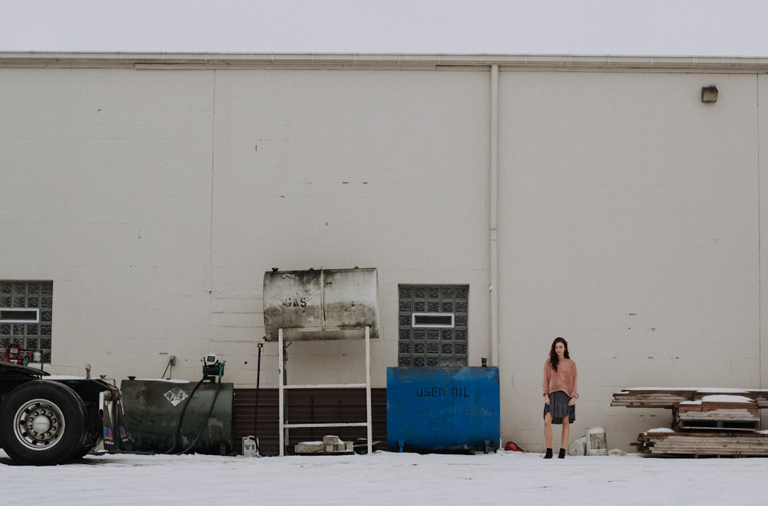 woman standing near blue container tank and white building during daytime