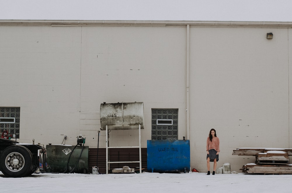 woman standing near blue container tank and white building during daytime