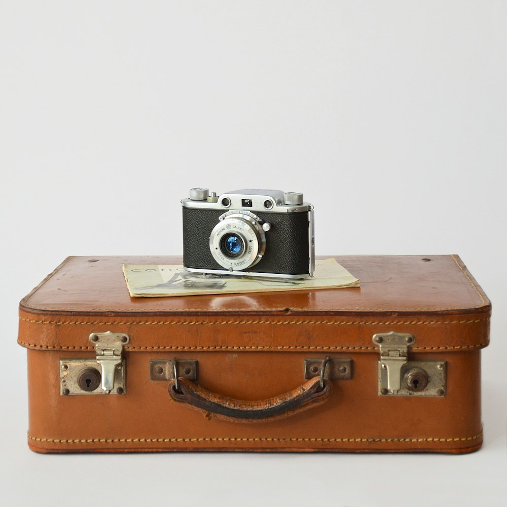 a camera sitting on top of a brown suitcase