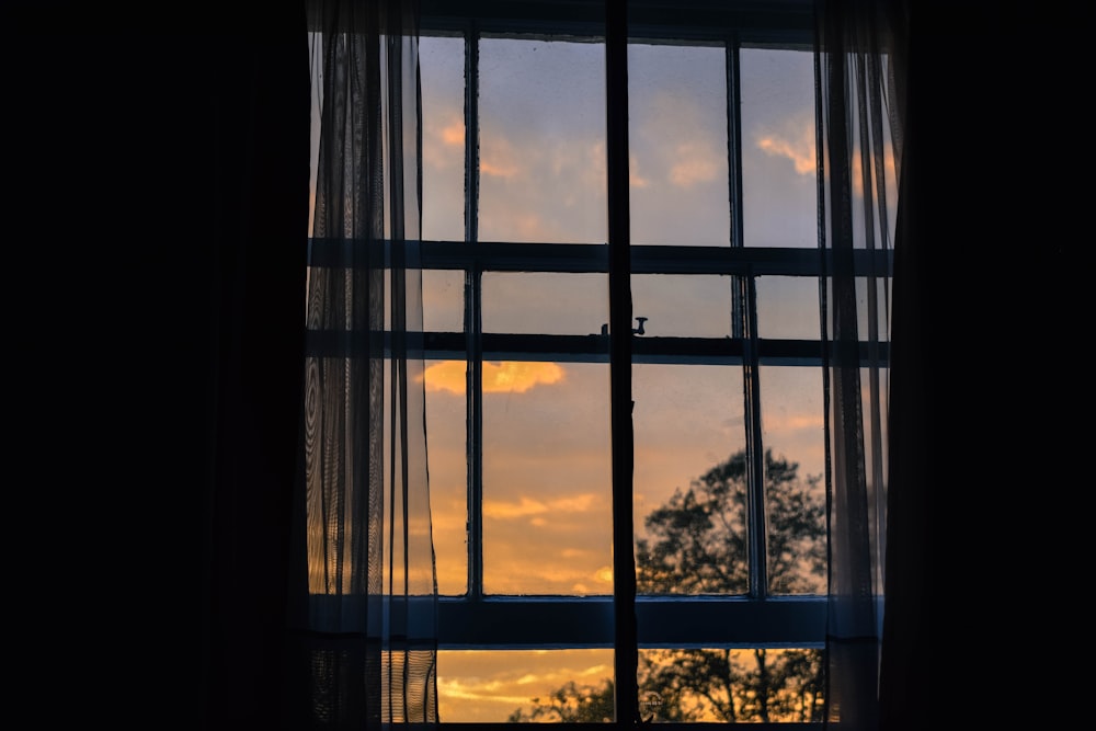 Foto de ventana de vidrio con marco azul con cortina