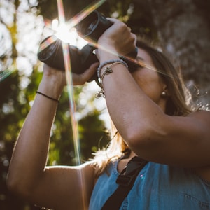 woman using binoculars in forest