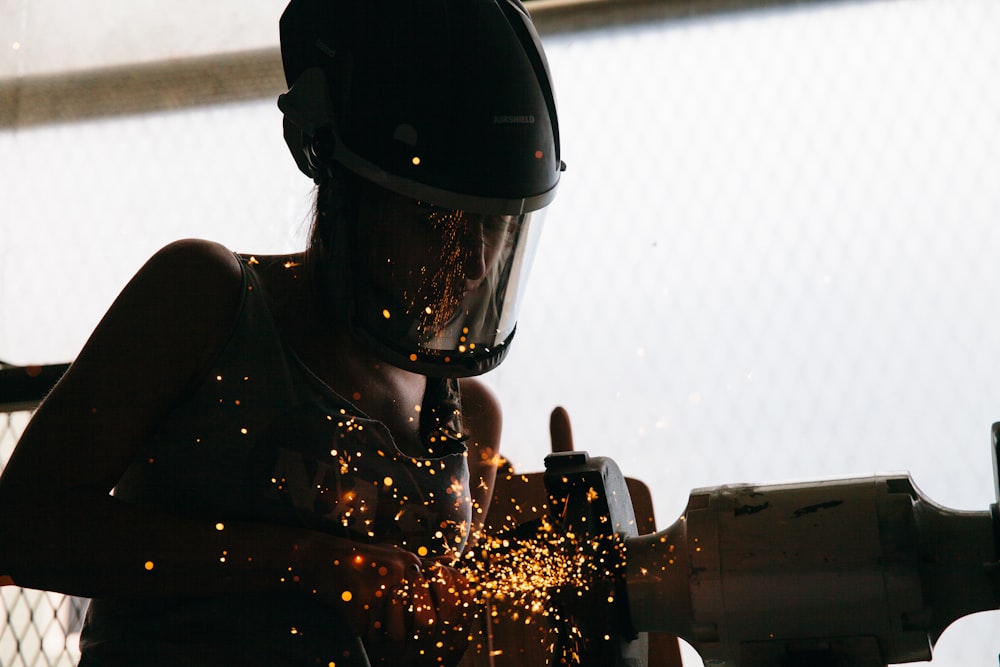 person standing beside gray bench grinder