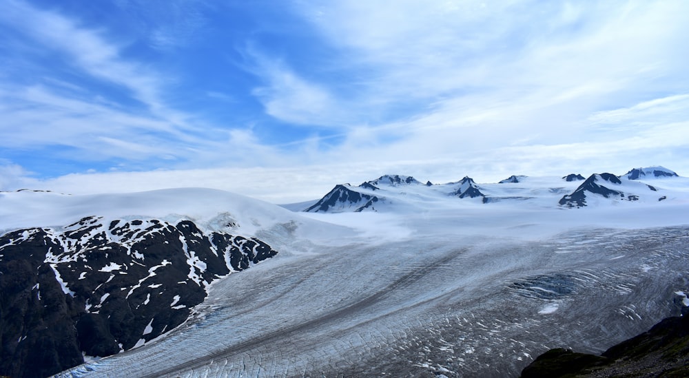 mountain covered with snow under white clouds