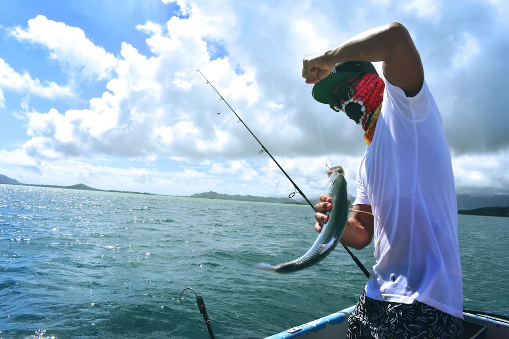 homme en t-shirt blanc tenant un poisson